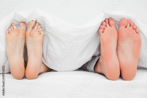 Photo: Two pairs of feet, in bed beside each other pointing straight up Two pairs of feet, in bed beside each other pointing straight up