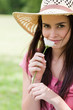 Photo: Young peaceful girl smelling a flower while standing in a park with a straw hat Young peaceful girl smelling a flower while standing in a park with a straw hat