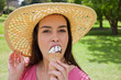Young attractive woman eating an ice cream while standing in the countryside