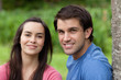 Young smiling couple standing side by side in the countryside