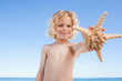 Smiling boy on the beach showing starfish