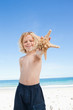Smiling boy on the beach with starfish