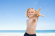 Cute boy on the beach showing his starfish