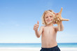 Boy on the beach with starfish giving thumb up
