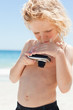 Boy at the beach taking a look at the screen of a digital camera