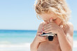 Boy looking at the screen of a digital camera at the beach