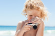 Boy looking at screen of a digital camera at the beach