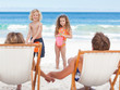 Siblings talking with their parents on the beach