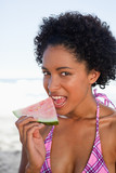 Photo: Young attractive woman looking at the camera while eating a piece of watermelon Young attractive woman looking at the camera while eating a piece of watermelon