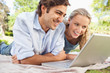 Photo: Couple lying on the lawn with their laptop Couple lying on the lawn with their laptop