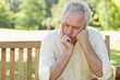 Man holding his face between his hands as he sits on a bench