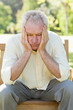 Man looking downwards while holding his face between his hands 