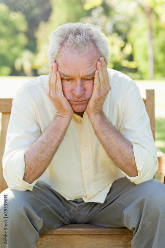 Photo: Man looking downwards while holding his face between his hands Man looking downwards while holding his face between his hands