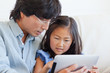 Photo: Close up of a father and daughter using a tablet together on the couch Close up of a father and daughter using a tablet together on the couch