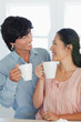 A couple look at each other as they hold a cup in hand