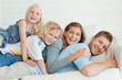 The family all lie on top of each other while lying across the couch