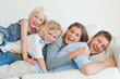 The laughing family lie across the couch on top of each other