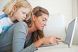 A woman types into her laptop as her child watches