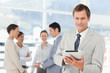 Smiling salesman with tablet computer and colleagues behind him