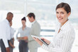Smiling saleswoman with her tablet computer and associates behind her