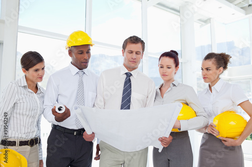 Photo: A group of architects reading off from some blueprints A group of architects reading off from some blueprints
