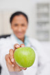 Big green apple being held by a doctor