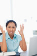 Foto: Upset secretary raising her hands while sitting at a desk Upset secretary raising her hands while sitting at a desk