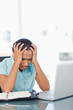 Foto: Upset secretary sitting at a desk in front of her laptop Upset secretary sitting at a desk in front of her laptop