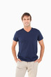 Smiling man standing upright with his hands in his pockets