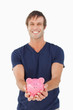 Smiling man holding a piggy bank