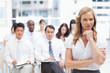 Businesswoman resting her chin on her hand while standing in front of her colleagues