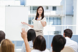 Photo: Woman smiling as she points to a member of the audience who has her hand raised Woman smiling as she points to a member of the audience who has her hand raised
