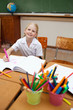 Smiling girl sitting at desk next to pen holders