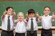 Smiling students in school uniforms giving thumbs up