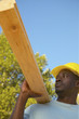 Male construction worker carrying two by fours