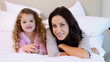 Mother and daughter lying on the bed