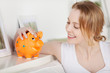 blonde frau mit sparschwein zuhause