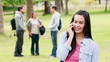 Video: Woman smiling while talking on a phone as her friends have a discussion in the background Woman smiling while talking on a phone as her friends have a discussion in the background