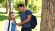 Video: Man reading a text message while leaning against a tree before hugging a woman and laughing Man reading a text message while leaning against a tree before hugging a woman and laughing
