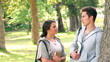 Video: Camera pans to show two friends talking as they stand by the trunk of a tree in the park Camera pans to show two friends talking as they stand by the trunk of a tree in the park