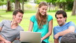 Video: Woman laughing and talking as she uses a laptop while sitting with her two friends in a park Woman laughing and talking as she uses a laptop while sitting with her two friends in a park