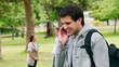 Video: Man talking and laughing on his mobile phone as he stands in a park Man talking and laughing on his mobile phone as he stands in a park