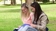 Video: Two friends laughing and talking as they read a book together in a park Two friends laughing and talking as they read a book together in a park