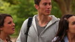 Video: Camera pans to show four friends looking at each other as the stand in a park Camera pans to show four friends looking at each other as the stand in a park