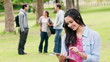 Woman using her tablet pc before looking at the camera as she stands in a park