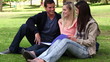 Video: Three friends laughing as they read a book together in a park Three friends laughing as they read a book together in a park