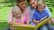 Video: A family turning the page of a book and then continuing to read before smiling towards the camera A family turning the page of a book and then continuing to read before smiling towards the camera