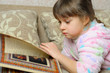 The little girl reads the book lying on a sofa