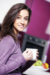 Beautiful young  woman having coffee while at the kitchen