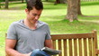 Video: Man reading a newspaper before looking at the camera as he sits on a bench Man reading a newspaper before looking at the camera as he sits on a bench